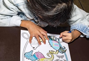 Pretty asian child left handed while doing a coloring activity w